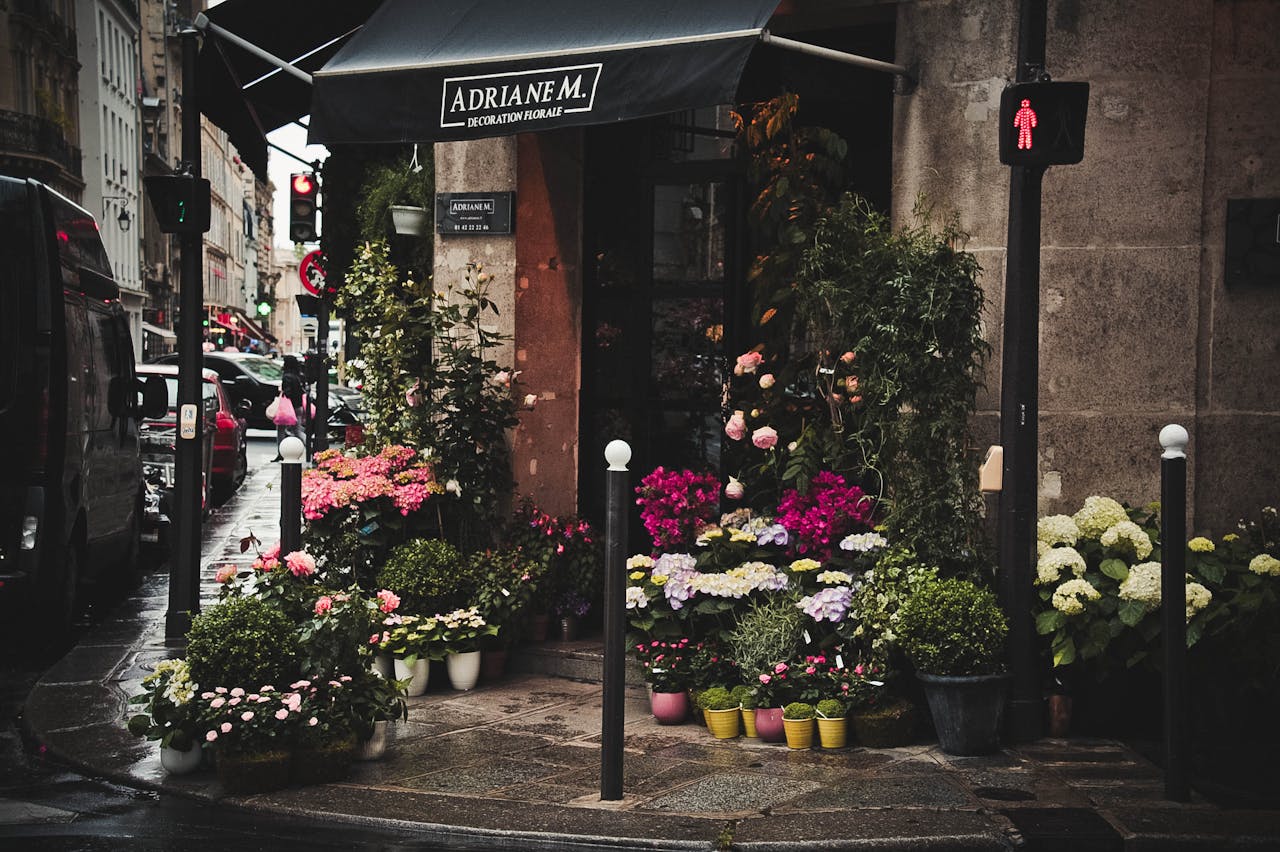A picturesque flower shop on a vibrant urban street with a variety of colorful blooms on display.